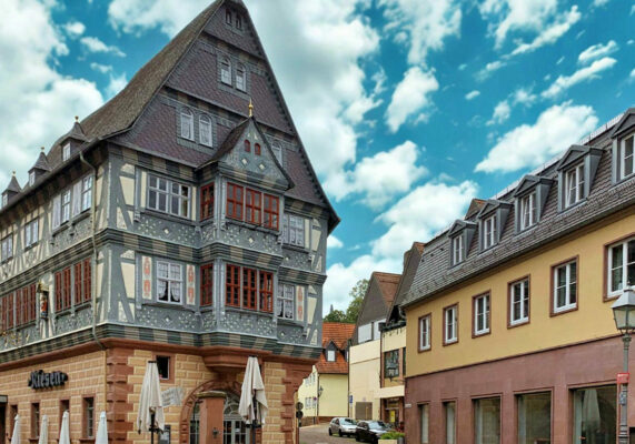 MainZauber Apartments früher MainTerrasse Miltenberg am Main - Luxuriöse Ferienwohnung in historischem Fachwerkhaus mit edlen Details, ruhige Lage, Nachbarhäuser gelb, blauer Himmel.