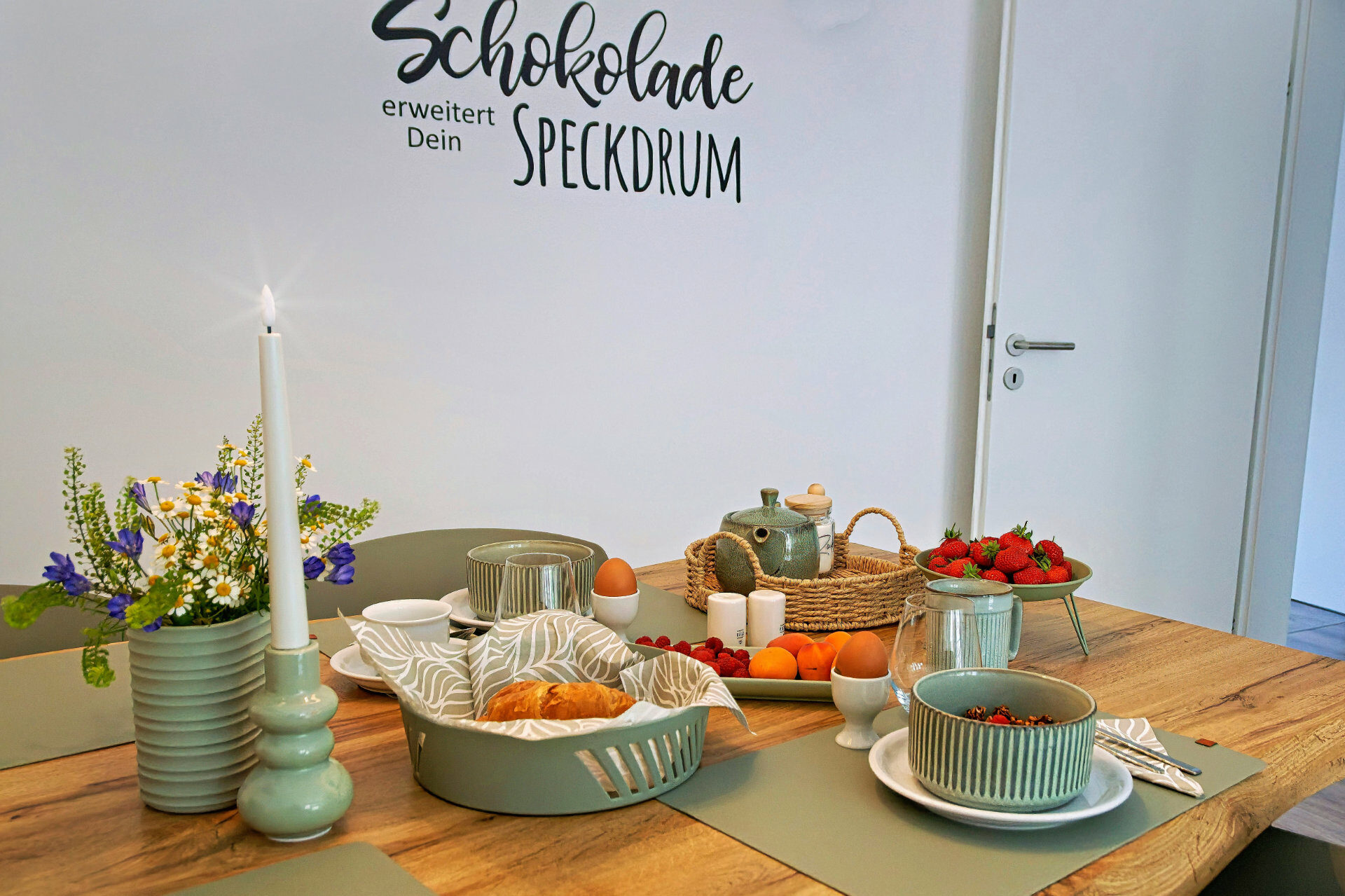 MainZauber Apartments früher MainTerrasse Miltenberg am Main - Luxuriöses Frühstück in stilvoller Ferienwohnung: Grünes Geschirr, Croissants, Obst & Deko im Altstadt-Apartment.