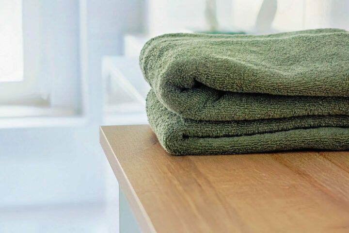 MainZauber Apartments früher MainTerrasse Miltenberg am Main - Zwei grüne, sorgfältig gefaltete Handtücher auf Holz in einer Luxus Ferienwohnung Altstadt - modernes, helles Badezimmer-Ambiente.