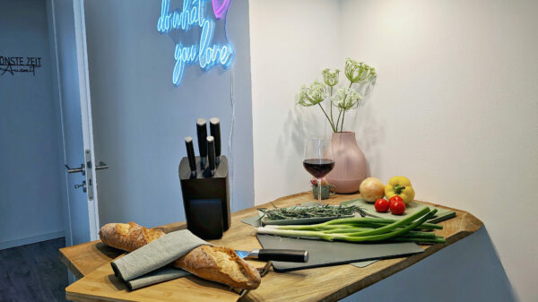 MainZauber Apartments früher MainTerrasse Miltenberg am Main - Gemütliche Küche in der Luxus-Ferienwohnung AltstadtZauber Miltenberg mit Holzarbeitsplatte, Deko, frischen Zutaten & Wein.