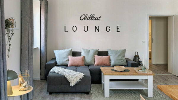 MainZauber Apartments früher MainTerrasse Miltenberg am Main - Luxuriöse Ferienwohnung in der Altstadt: Modernes Wohnzimmer mit dunklem Sofa, Pastellkissen, Holztisch - ideale Unterkunft.