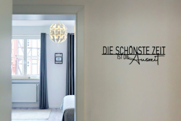 MainZauber Apartments früher MainTerrasse Miltenberg am Main - Modernes, minimalistisches Schlafzimmer in Luxus-Ferienwohnung mit grauen Vorhängen, Pendelleuchte, zentral in Miltenberg.