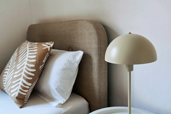 MainZauber Apartments früher MainTerrasse Miltenberg am Main - Ein stilvolles, komfortables Ferienapartment: Weiß bezogenes Bett, beige Kissen, edler Nachttisch mit moderner Lampe.