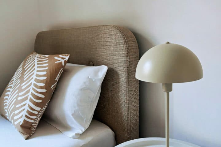 MainZauber Apartments früher MainTerrasse Miltenberg am Main - Ein stilvolles, komfortables Ferienapartment: Weiß bezogenes Bett, beige Kissen, edler Nachttisch mit moderner Lampe.
