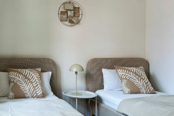 MainZauber Apartments früher MainTerrasse Miltenberg am Main - Zwei Einzelbetten mit beigen Kopfteilen und weißer Bettwäsche im Luxus-Apartment, ideal für Ihren Urlaub in der Altstadt.