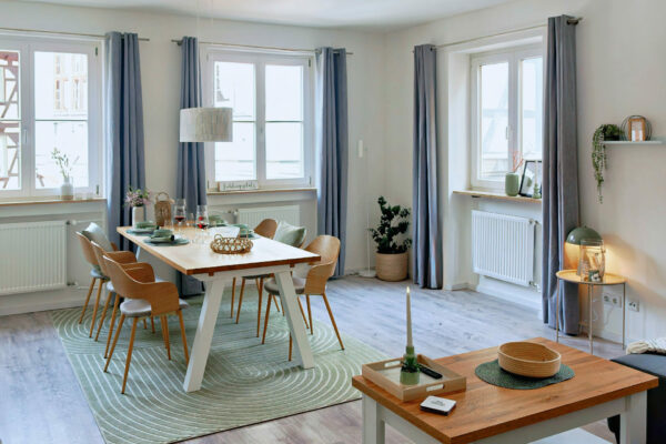 MainZauber Apartments früher MainTerrasse Miltenberg am Main - Helle, moderne Ferienwohnung in der Altstadt: Luxus-Apartment mit großem Esstisch, stilvollem Ambiente und großen Fenstern.