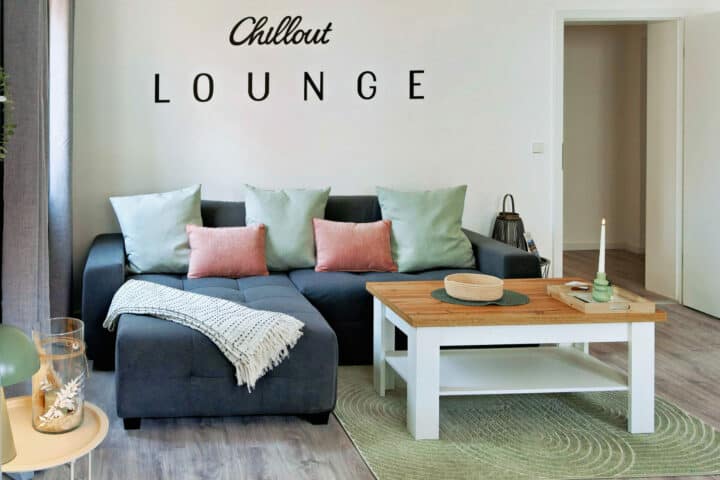 MainZauber Apartments früher MainTerrasse Miltenberg am Main - Modernes Wohnzimmer in luxuriöser Ferienwohnung Altstadtzauber mit grauem Sofa, Pastellkissen und stilvollen Details.