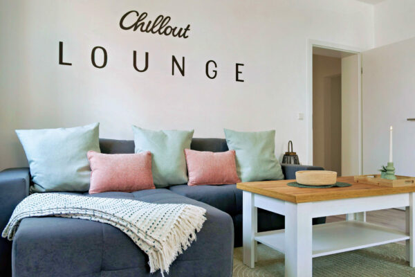 MainZauber Apartments früher MainTerrasse Miltenberg am Main - Gemütliches Wohnzimmer einer Luxus-Ferienwohnung in Miltenberg mit grauem Sofa, Holztisch und stilvollem Lounge-Flair.