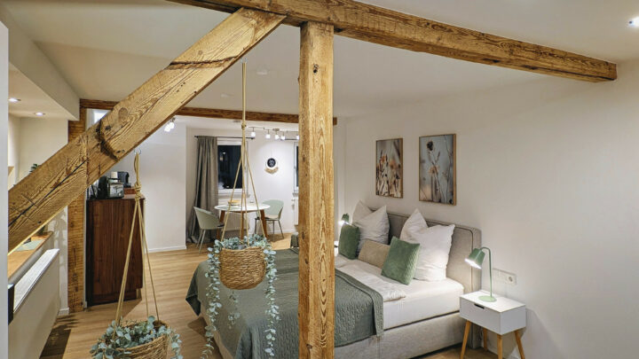 MainZauber Apartments früher MainTerrasse Miltenberg am Main - Entdecken Sie das ultimative Ferienwohnungserlebnis in diesem gemütlichen, modernen Dachgeschoss-Refugium. Dieses luxuriöse Urlaubsapartment ist perfekt für Ihren nächsten Kurzurlaub und verfügt über ein charmantes Schlafzimmer mit freiliegenden Holzbalken, die Charakter und Wärme ausstrahlen. Entspannen Sie sich auf dem bequemen Doppelbett mit eleganter grün-weißer Bettwäsche, umgeben von durchdachten Details wie zwei Nachttischen mit schicken Lampen. Genießen Sie Mahlzeiten in Ihrem intimen Essbereich inmitten von Hängepflanzen, die Ihrer Unterkunft einen Hauch von Natur verleihen. Die sanfte Beleuchtung im gesamten Apartment schafft eine ruhige Atmosphäre, in die Sie nach der Erkundung Ihres Reiseziels gerne zurückkehren werden. Erleben Sie unvergleichlichen Komfort in diesem exquisiten Ferienapartment!